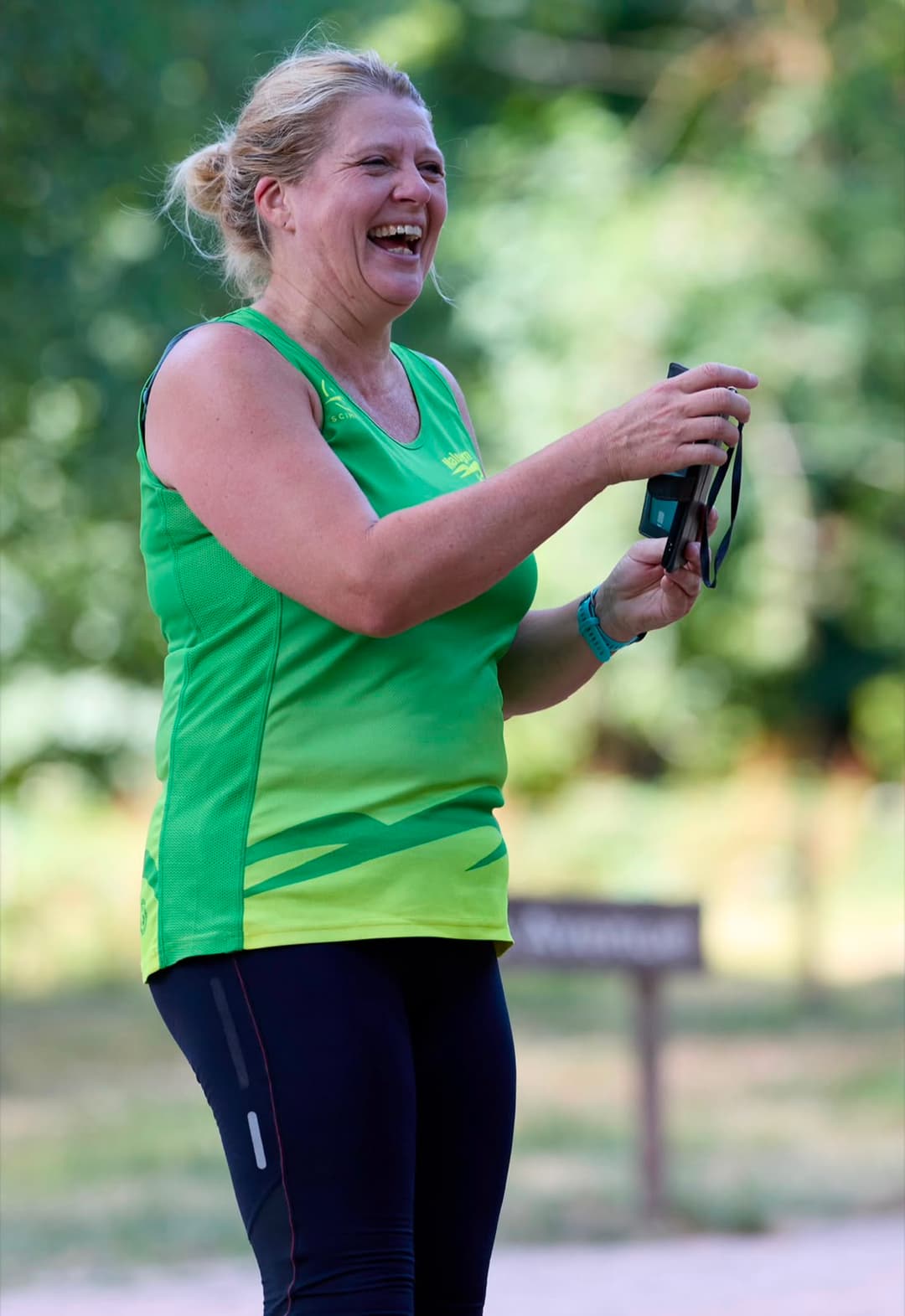 A member in club colours laughing while timing runners